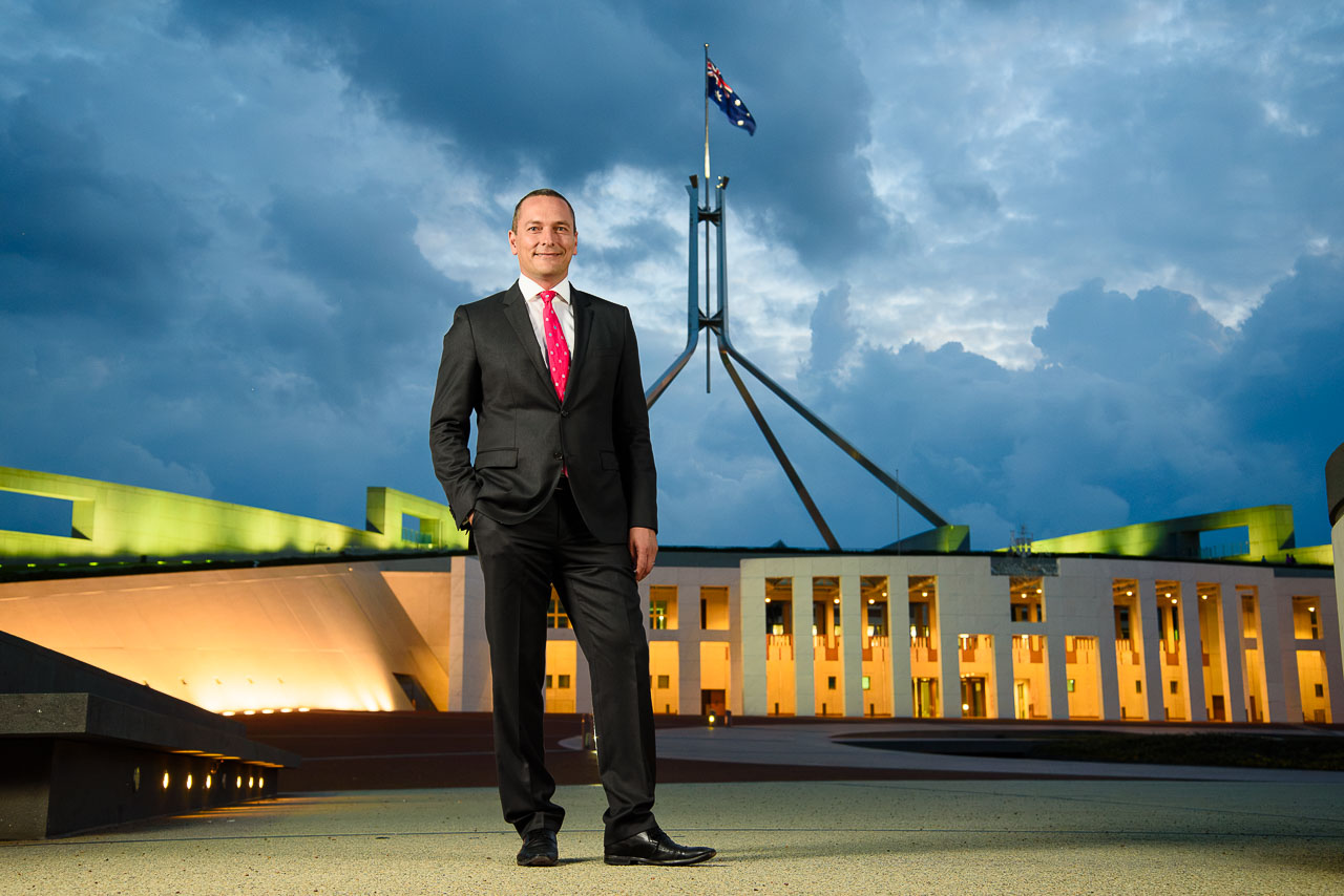 Canberra political journalist standing in front of Parliament House at night